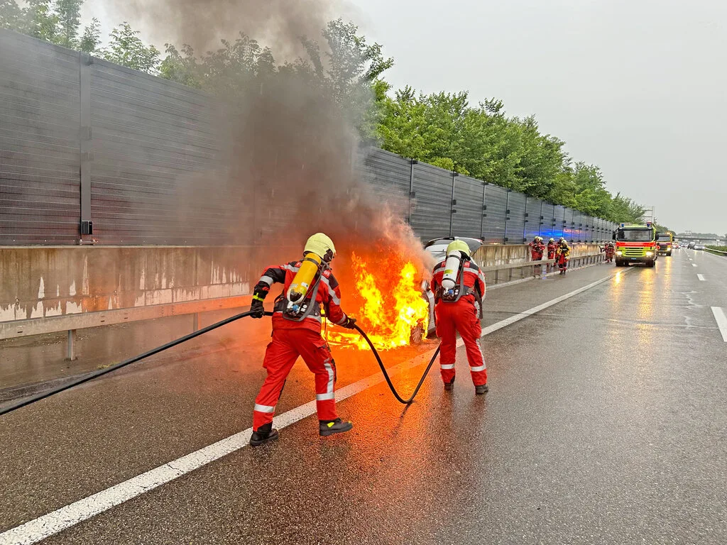 Die Feuerwehr hatte den Brand rasch unter Kontrolle. Ein brennendes Auto und löschende Feuerwehrleute